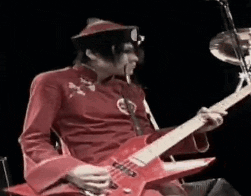 a man in a red outfit is playing a red electric guitar .