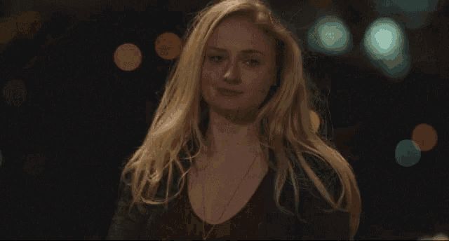 a woman with blonde hair is standing in front of a dark background