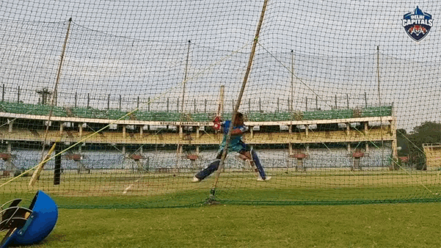 a cricket player is hitting a ball in a net with the word capitals on it