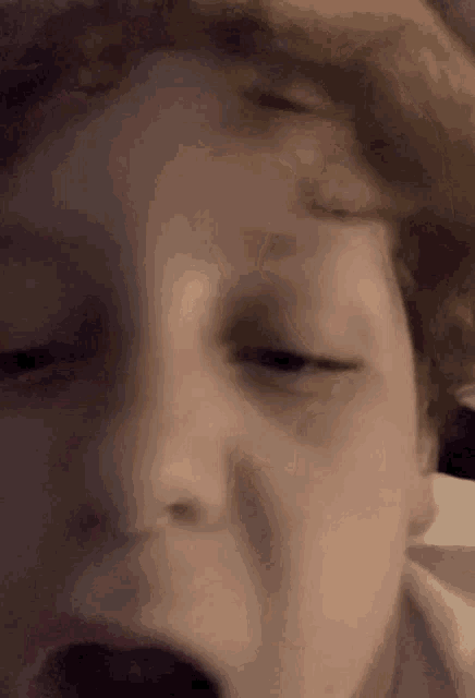 a close up of a child 's face with his eyes closed .