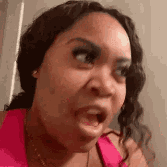 a woman in a pink tank top is making a funny face .