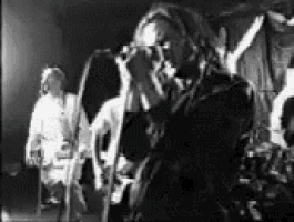 a black and white photo of a person singing into a microphone .