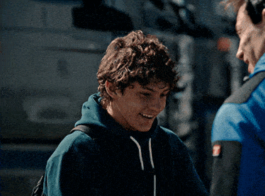 a young man wearing a blue jacket with a red emblem on the sleeve