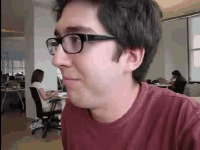 a man wearing glasses and a red shirt is smiling