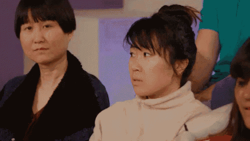 a group of women are sitting in a room and one woman is making a funny face .