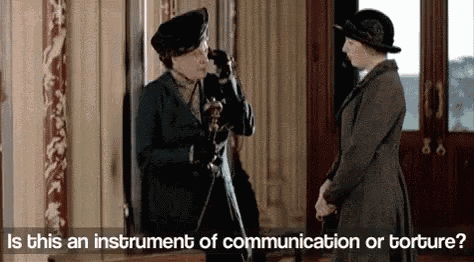 two women are standing next to each other in a room talking on a cell phone .