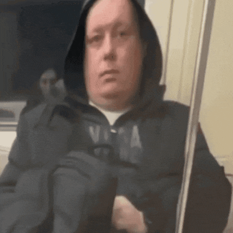 a man wearing a hooded jacket is sitting on a train .