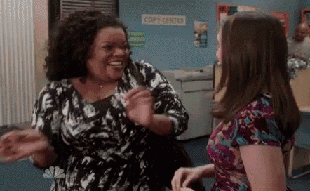 two women are standing next to each other in an office .