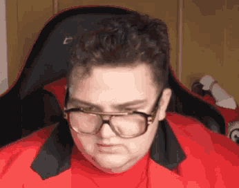 a man wearing glasses is sitting in a chair .