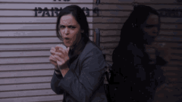 a woman is eating a sandwich in front of a garage door that says parking