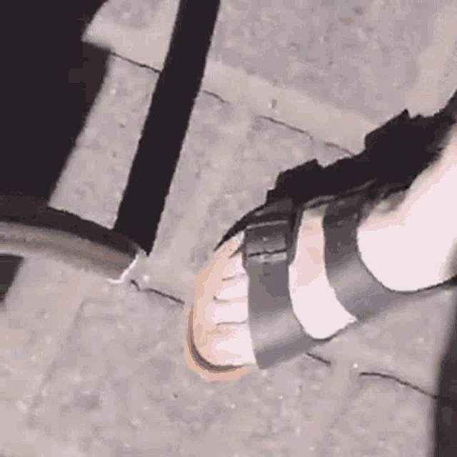 a close up of a person 's foot wearing a pair of black sandals .