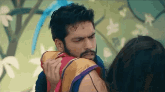 a man and a woman are hugging each other in a room . the man is holding the woman 's shoulder .