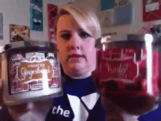 a woman holding a jar of gingerbread scented candles