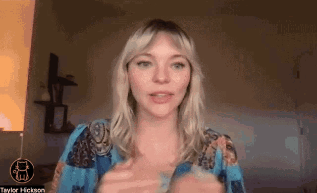 a woman in a blue dress is talking on a video call with taylor hickson