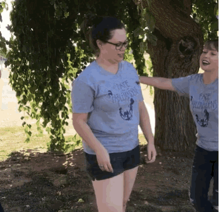 a woman wearing a t-shirt that says " fate unleashed " is standing next to another woman