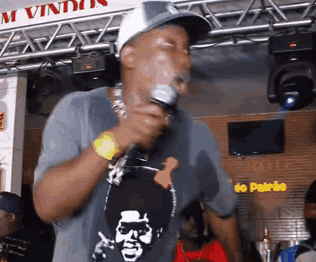 a man is singing into a microphone in front of a sign that says " m vindo "