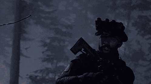 a man with a beard is holding a rifle in the dark
