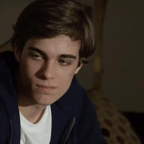 a close up of a young man 's face with a white shirt and a blue jacket