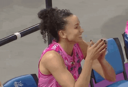 a woman in a pink tank top is sitting next to a woman in a blue chair .