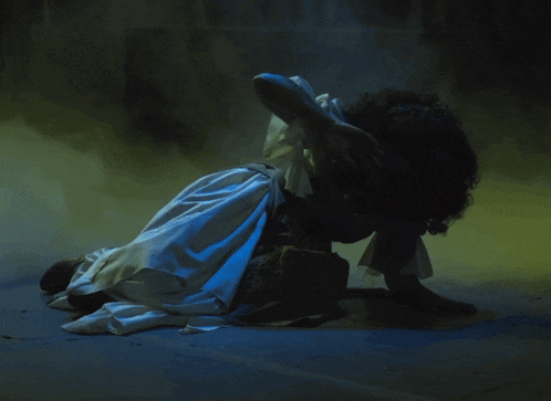 a woman in a white dress is laying on the floor in a foggy room