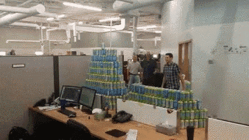 a bunch of cans are stacked on top of each other in a cubicle