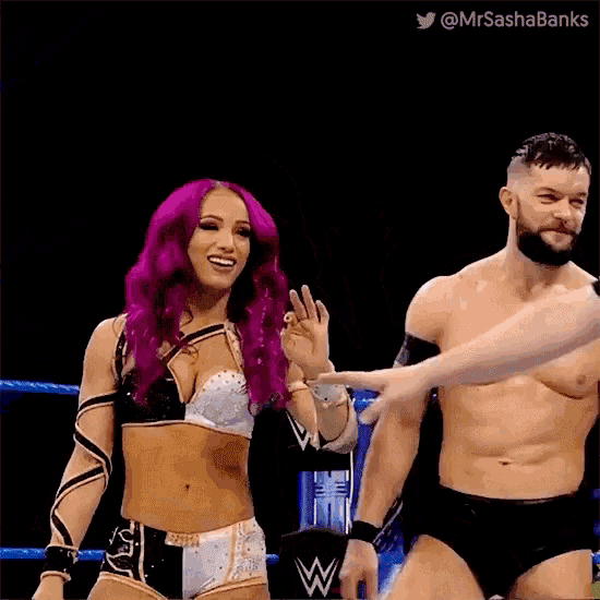 a man and a woman are standing in a wrestling ring . the woman is wearing purple hair .