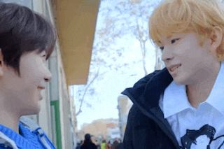 a couple of young men are standing next to each other on a sidewalk .