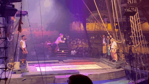 a group of people standing on a stage in front of a purple light