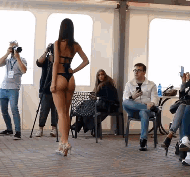 a woman in a bikini is being photographed by a man wearing a name tag that says ' a ' on it