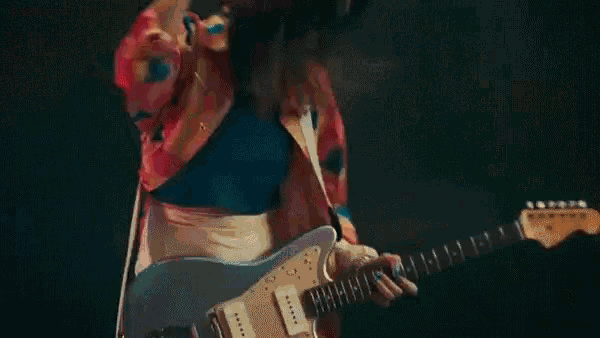 a woman in a colorful shirt is playing an electric guitar on a stage .