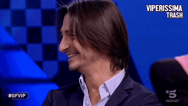 a man in a suit is smiling in front of a checkered background with the hashtag #gfvip on it