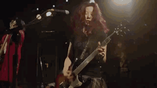 a woman with red hair is playing a guitar on stage .