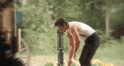 a man in a white tank top is standing next to a blue pipe