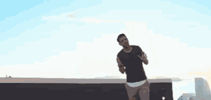 a man is raising his arms in the air in front of a body of water