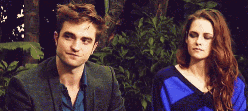 a man in a suit and a woman in a blue sweater are standing next to each other .