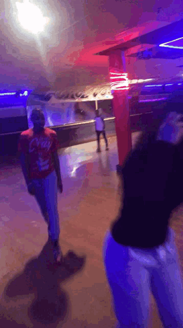 a man in a red shirt that says ' coca cola ' on it is walking on a roller rink