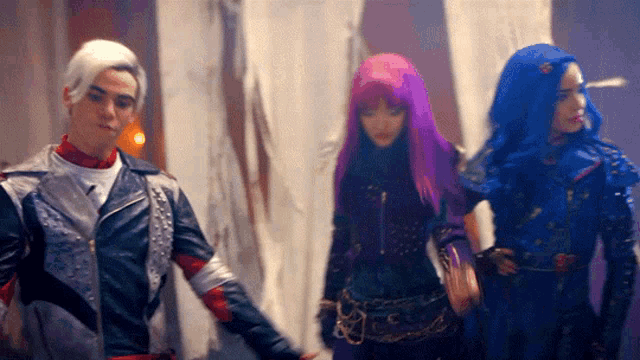 a man in a leather jacket is standing next to two women with purple hair