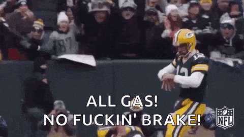 a green bay packers football player is running with the ball in front of a crowd of fans .