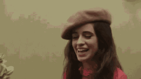 a woman wearing a beret and a red shirt is smiling and looking at the camera .