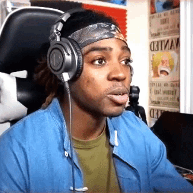 a man wearing headphones and a headband with the word wanted on the wall behind him