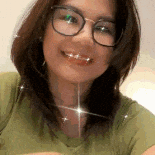 a woman wearing glasses and a green shirt smiles at the camera