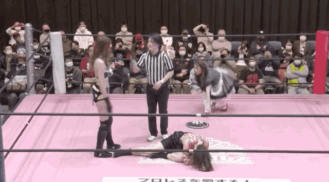 a woman is laying on the ground in a wrestling ring while a referee talks to her
