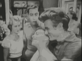 a black and white photo of a group of people standing next to each other in a room .