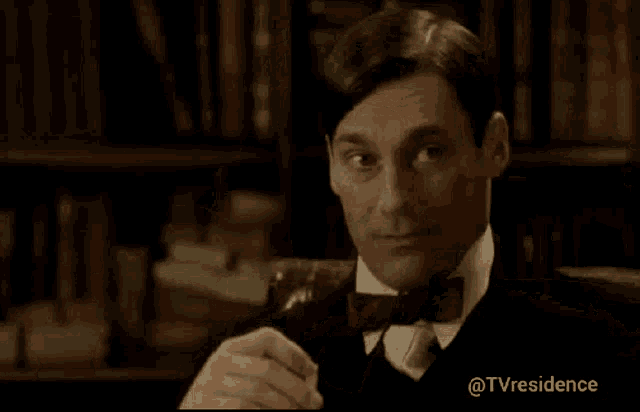 a man in a suit and bow tie is holding a glass of something