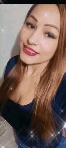 a woman with long brown hair is smiling and wearing a blue shirt