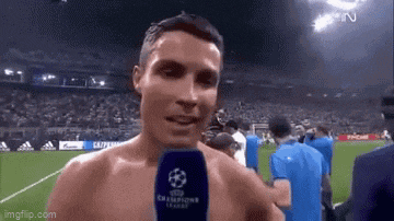 a shirtless man is standing on a soccer field with a microphone .