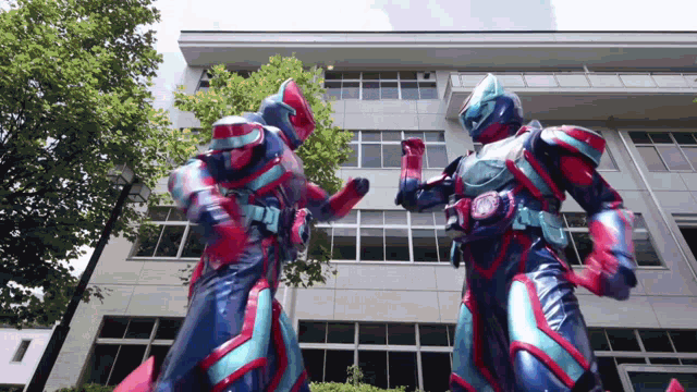 two robots are standing in front of a building with trees in the background