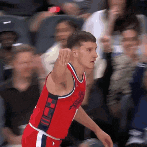 a basketball player wearing a red jersey with the word washington on it stands in front of a crowd
