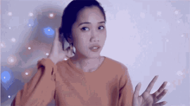 a woman in an orange sweater is making a peace sign