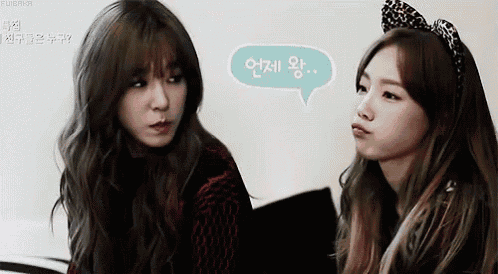 two young women are sitting next to each other and talking to each other .